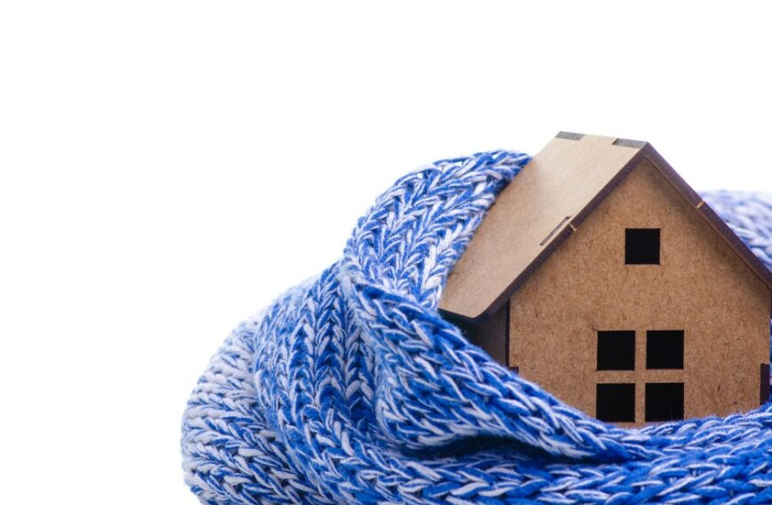 Ein in eine blaue Decke gehülltes Haus, das nach dem Gebäudeenergiegesetz einer Sanierung unterzogen wird, auf dem ein Holzhaus als zusätzliche Wärme dient