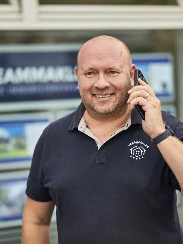 Ein Mann im Poloshirt, der mit einem Handy telefoniert.