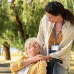 Eine Seniorin in ihrem Rollstuhl und ihre Pflegerin